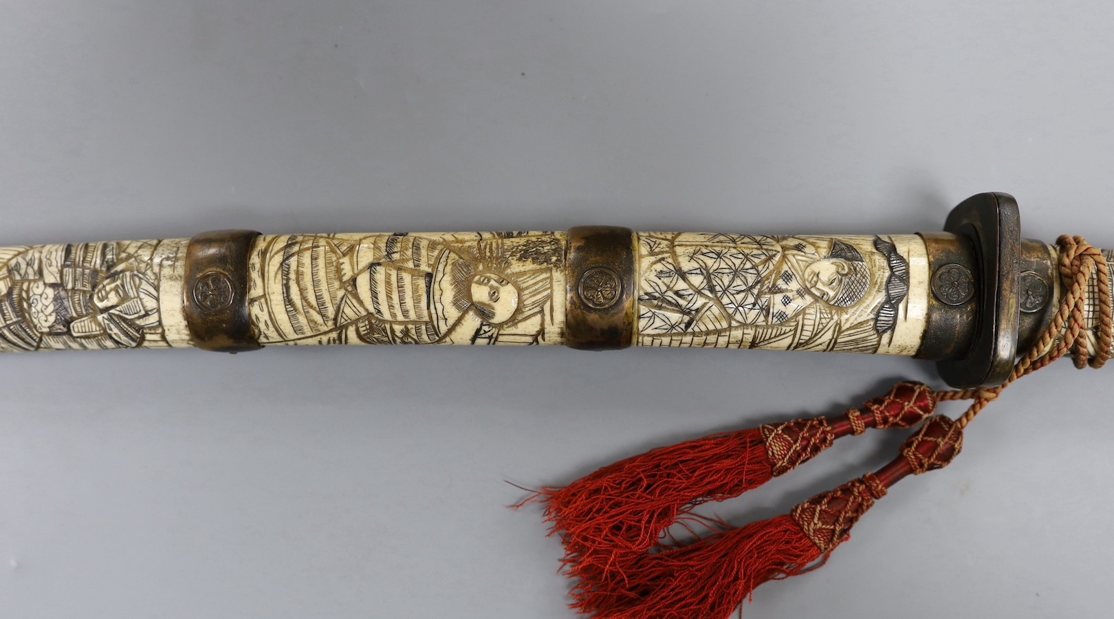 A late 19th century Japanese wakizashi sword, the blade 47.5cm, with sectional stag's horn scabbard and hilt carved with warriors and other figures, gilt metal mounted